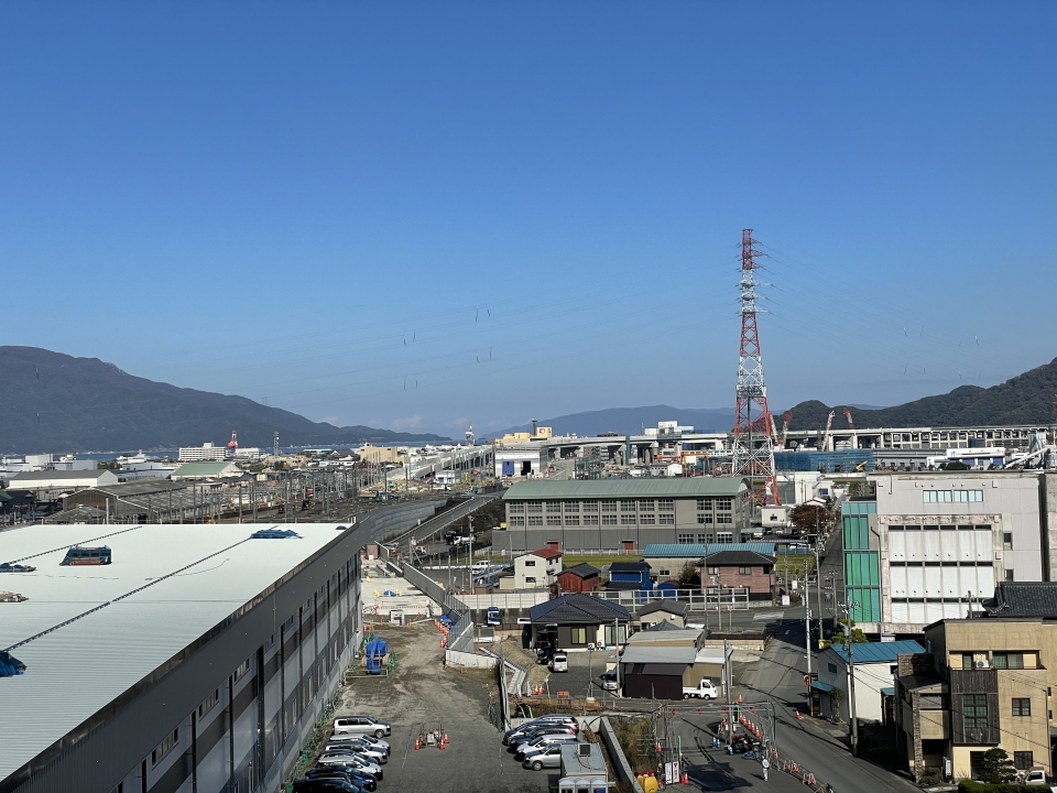ニュース画像 4枚目：総合事務所屋上から 敦賀駅まで続く高架橋と、中央遠くに水島の姿を望む