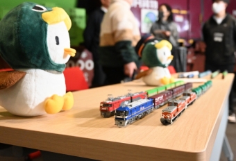 ニュース画像：ジェイアールエフ商事社長の花岡俊樹さんの私物の鉄道模型と「かもまるくん」