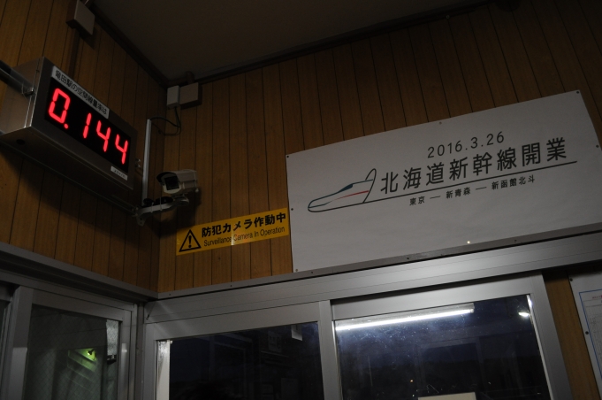 鉄道乗車記録の写真:駅舎・駅施設、様子(3)        「14日後に開通予定の北海道新幹線のポスター(右)と、空間線量計(左)。「0.144μ㏜/h」と表示。1時間当たりのマイクロシーベルト。」