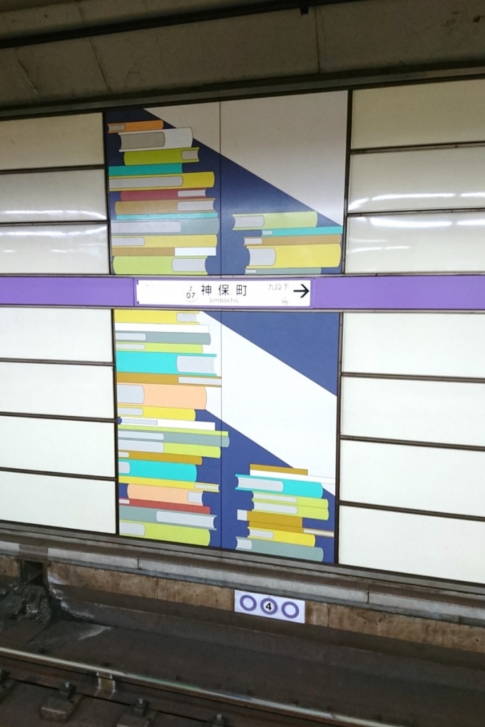 鉄道乗車記録の写真:駅名看板(1)        「本の街・神保町だけあって，駅名標の周りには本があしらわれたデザインとなっていました．」
