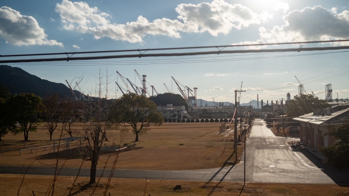 鉄道乗車記録の写真:車窓・風景(6)        「造船所のクレーンを遠目に見ながら、海上自衛隊の敷地の横を通り抜けて呉駅に入ります。」