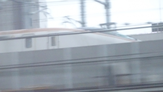 鉄道乗車記録の写真:車窓・風景(23)        「金沢を出発してすぐ脇の高架線ではもうすぐ開業する北陸新幹線のE7系(W7系？)が試運転しています。
トワイライトを廃止に追い込んだ憎き奴と思いながら撮影
今走行している線路ももうじきJRでは無くなると思うと複雑な気分に･･･」